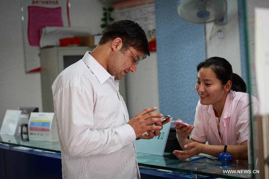 Mubeen Abdul (L), a student from Pakistan, talks with an alumna in a health clinic in Dongcun community in Nantong, east China's Jiangsu Province, June 28, 2013. Mubeen is a fresh graduate seeking for a job in Nantong from Nantong University, majoring in clinical medicine. He has rented a house and attended many job fairs in a month. No answer from employers and low income from part-time job exerted much pressure on him. Finally he got a job for reception of foreign guests and management in Nantong First People's Hospital on July 1, 2013. "I love China and I will continue studying for master's degree and qualification of medical practitioners," said Mubeen. (Xinhua/Huang Zhe)