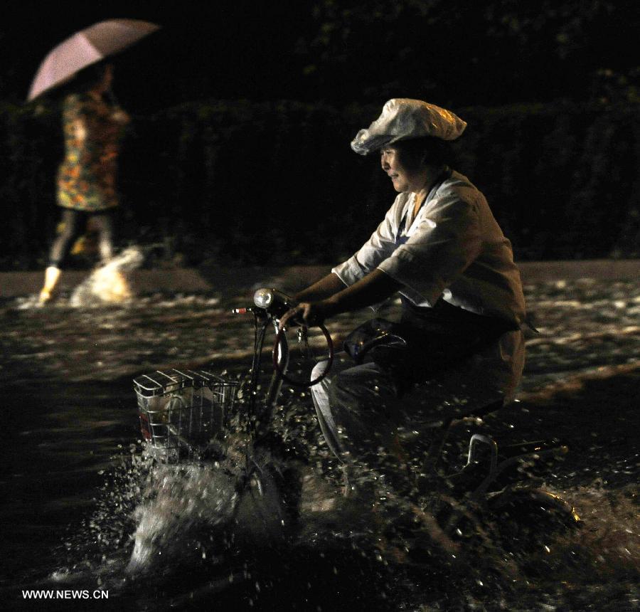 A citizen rides electric bicycle on a waterlogged road in Tianjin, north China, July 4, 2013. A rainstorm hit Tianjin on Thursday, causing waterlogging in part of the city. (Xinhua/Yue Yuewei) 