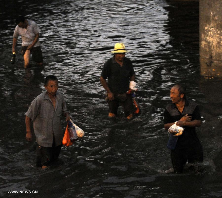 Pedestrains walk on a waterlogged road in Tianjin, north China, July 4, 2013. A rainstorm hit Tianjin on Thursday, causing waterlogging in part of the city. (Xinhua/Yue Yuewei) 