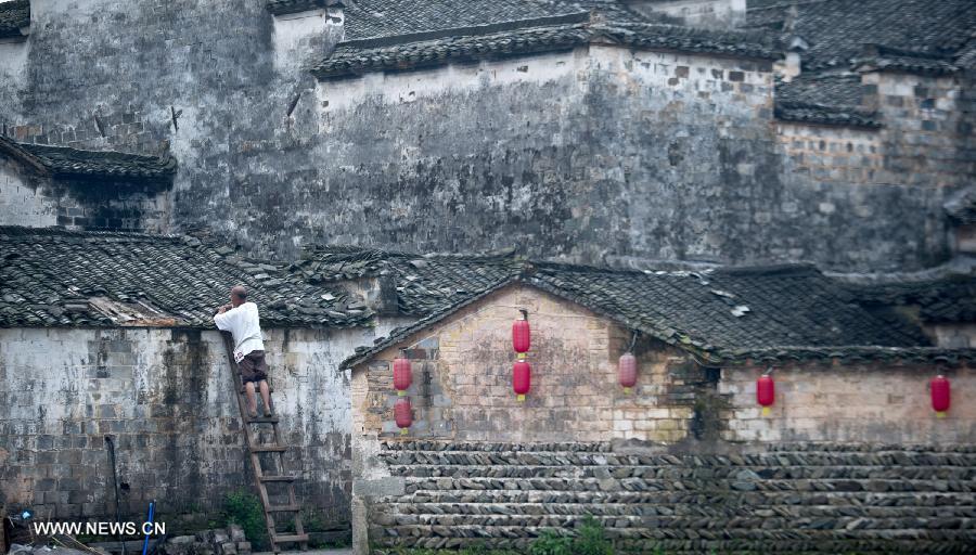 A worker repairs the roof of a building at Hongcun, an ancient village founded in 1131 in Huangshan City, east China's Anhui Province, July 3, 2013. Listed as a world cultural heritage site, the village preserved to a remarkable extent the surviving examples of Anhui-style architecture and traditional lifestyle. (Xinhua/Guo Chen) 