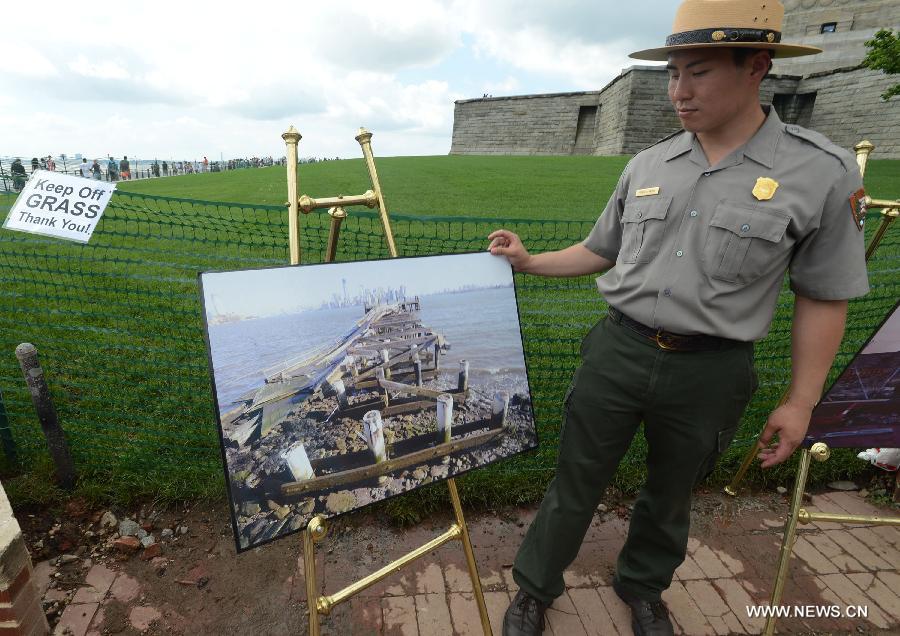 A ranger shows a picture of the aftermath of Hurricane Sandy besides the Statue of Liberty at Liberty Island in New York, the United States, on July 4, 2013, the U.S. Independence Day. The Statue of Liberty and Liberty Island reopened to the public on Thursday for the first time since Hurricane Sandy made landfall on Oct. 29, 2012. (Xinhua/Wang Lei) 