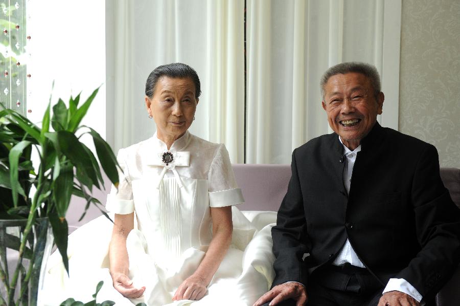 A couple pose for photos in wedding outfits in Hefei, July 4, 2013. (Xie Chen/Xinhua)