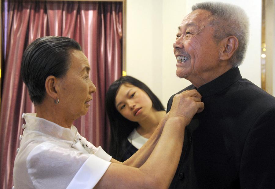 A woman adjusts her husband's suit before sitting for free wedding photos, in Hefei, July 4, 2013.(Xie Chen/Xinhua)