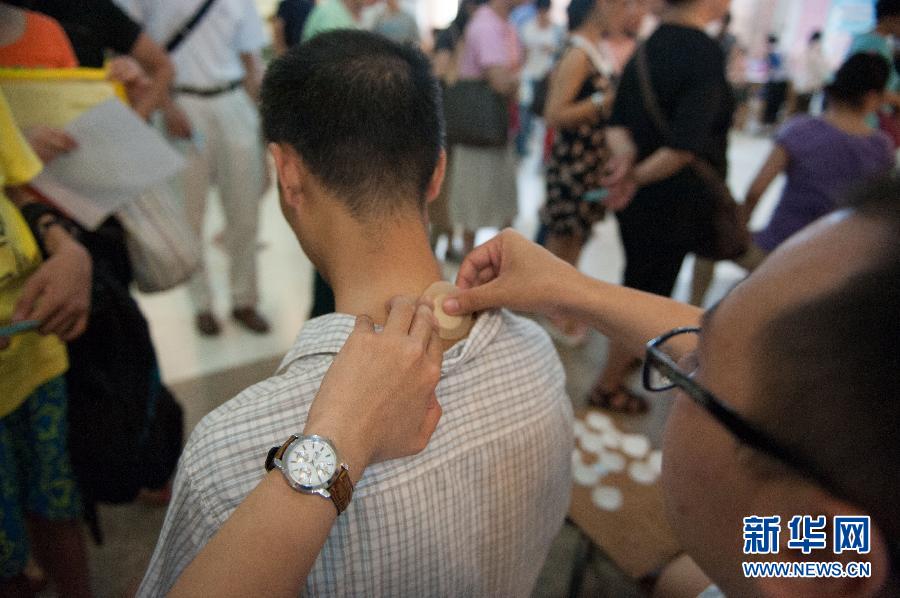 A doctor applies "hot summer days plaster medicine" to a man at the Guangdong Provincial Traditional Chinese Medical Hospital July 3, 2013. [Photo: Xinhua/Mao Siqian] 