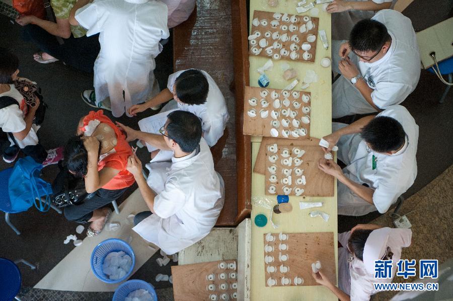 Doctors apply "hot summer days plaster medicine" to local residents at the Guangdong Provincial Traditional Chinese medical hospital July 3, 2013. [Photo: Xinhua/Mao Siqian] 