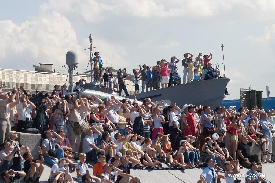 People watch the performance of Russia's aerobatics teams during the 6th International Maritime Defence Show in St.Petersburg, Russia, on July 4, 2013. The aerobatic teams will entertain crowds t the 6th International Maritime Defence Show to be held here from July 3-7. (Xinhua/Konkov)  