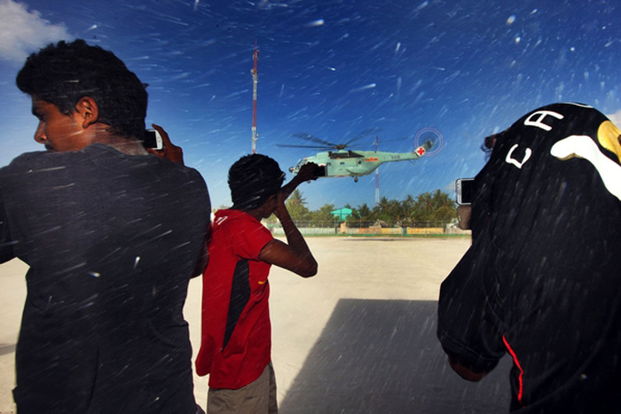 Local residents in a remote island of Maldives wait while a Chinese naval medical helicopter lands on a playground on July 2, 2013. It is the first time that the Chinese navy's medical helicopter was involved in a medical mission outside China. The helicopter concluded the mission the same day, diagnosing and treating more than 220 patients in Maldives. The mission started on July 1.  (Photo/Xinhua)