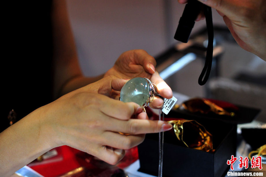 An exhibitor shows a precious stone to a visitor at 2013 Beijing Summer Jewelry Show, which kicked off on July, 4 and attracted nearly 200 jewelers with various jewels made of crystals, agates, ambers, rubies, jades, diamonds and other precious stones. (Chinanews.com/Jin Shuo)