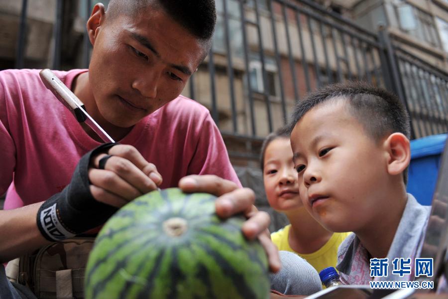 Two kids look at Shen carving on his watermelon at his stall in northwest China's Lanzhou on July 4, 2013. (Photo/Xinhua)