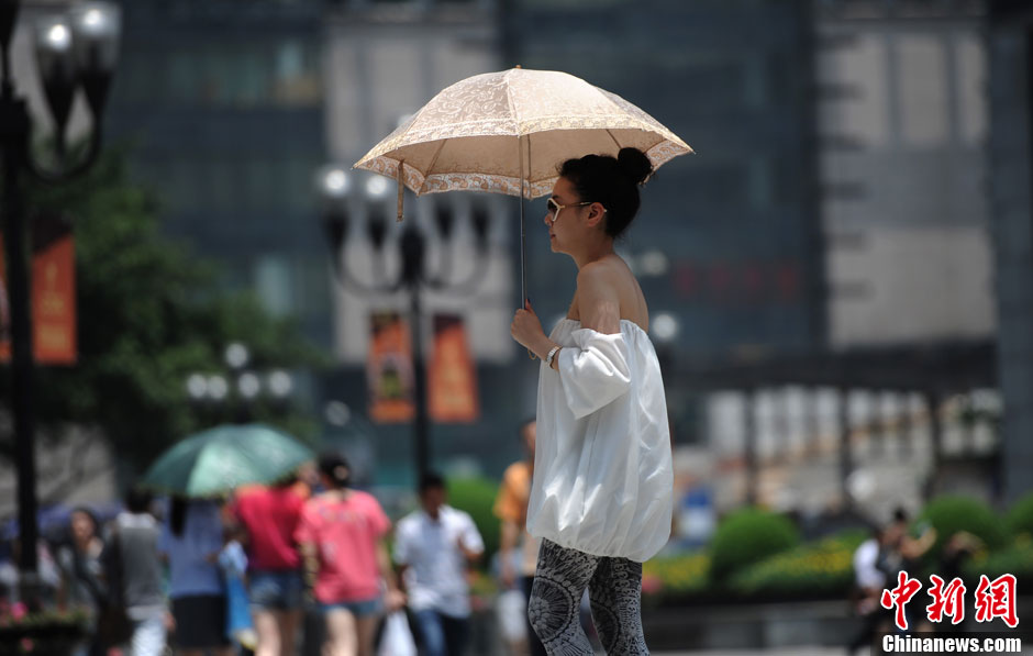 A woman in summer dress walks in the street in Chongqing on June 17, 2013. The temperature in Chongqing reached nearly 40 degrees Celsius on the day. The weather station of Chongqing issued an orange warning of high temperature. (Photo/Chinanews) 