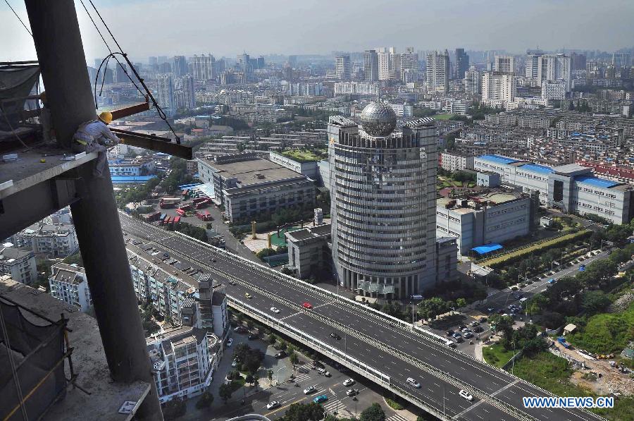 Construction workers reinforce bolts on the 30th floor of a high building in the heat in Ningbo City, east China's Zhejiang province, July 5, 2013. (Xinhua/Hu Xuejun) 