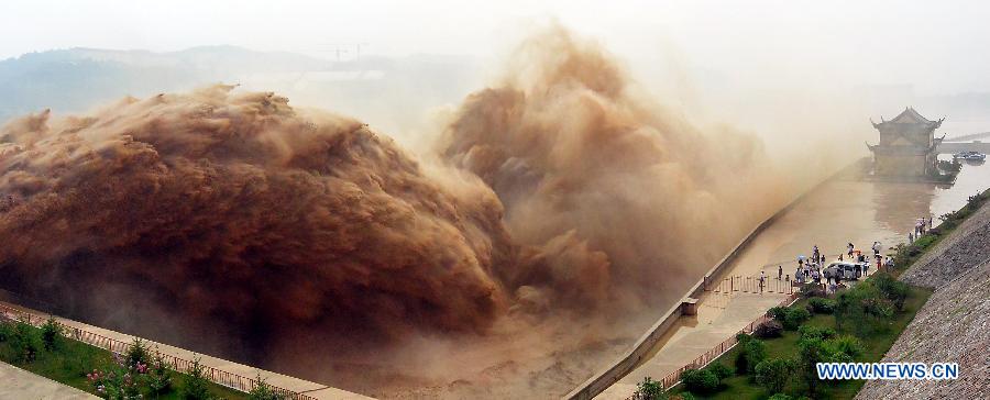 Tourists watch water gushing out from the Xiaolangdi Reservoir on the Yellow River during a sand-washing operation in Luoyang, central China's Henan Province, July 5, 2013. The on-going operation, conducted on Friday, works by discharging water at a volume of 2,600 cubic meters per second from the reservoir to clear up the sediment in the Yellow River , the country's second-longest waterway. Speeding currents would carry tons of sand into the sea. The Yellow River has been plagued by an increasing amount of mud and sand. Each year, the river bed rises as silt deposits build up, slowing the water flow in the lower reaches. (Xinhua/Wang Song) 