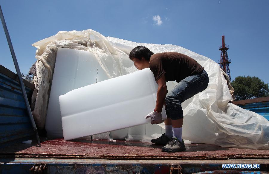 A worker uplifts an ice cube at the Beijing Xinfadi Agricultural Products Market in Beijing, capital of China, July 5, 2013. With the temperature keeping climbing, sales of ice cubes increased in Beijing in recent days. (Xinhua) 