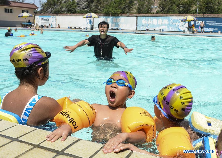 Children take part in a training in a swimming pool in Urumqi, capital of northwest China's Xinjiang Uygur Autonomous Region, July 5, 2013. Some 450,000 pupils and middle school students have started their summer vacation recently. With less homework assigned by the school, they are able to enjoy a relaxing vacation this summer. (Xinhua/Wang Fei) 