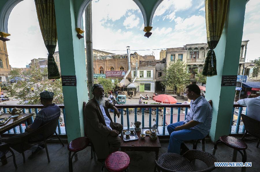 People have tea at an old teahouse near the Id Kah Square in Kashgar, northwest China's Xinjiang Uygur Autonomous Region, July 5, 2013. With simple decoration, the teahouse is located at the second floor of an old-fishioned building and is favored by the old of Uygur ethnic group. They usually enjoy drinking tea and chatting after every morning prayer. (Xinhua/Shen Qiao)