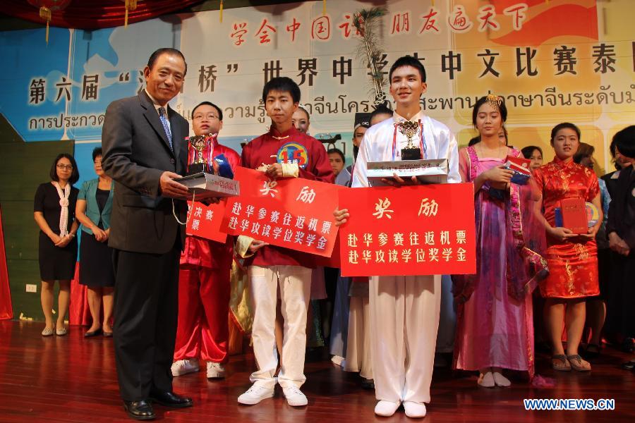 Chinese Ambassador to Thailand Guan Mu (L Front) awards trophies to the two winners of the final round of the sixth "Chinese Bridge" language proficiency competition for middle school student in Bangkok, capital of Thailand, July 5, 2013. A total of 17 Thai middle school students from all over the nation competed in the final. (Xinhua/Li Li) 