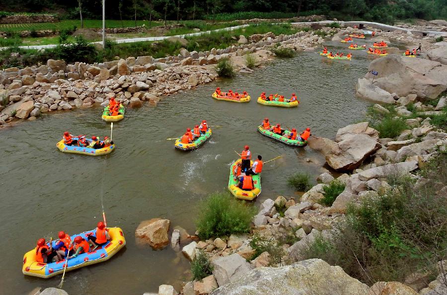 Tourists navigate a river during a river rafting festival at Jincun Township in Ruyang County, central China's Henan Province, July 6, 2013. (Xinhua/Wang Song)