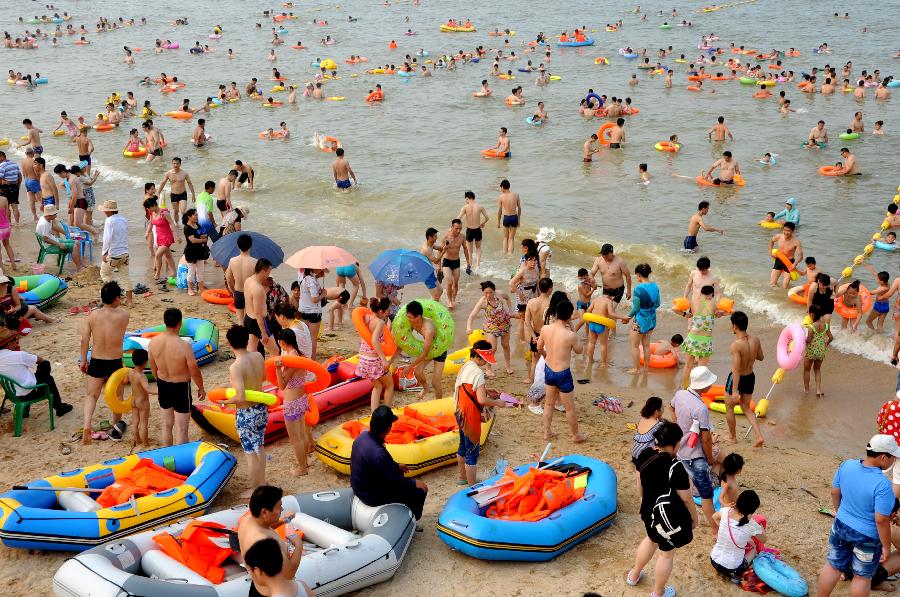 Tourists enjoy coolness at the Dashawan bathing beach in Lianyungang, east China's Jiangsu Province, July 6, 2013. The beach entered its tourism peak season with the rising temperature. (Xinhua/Wang Chun)