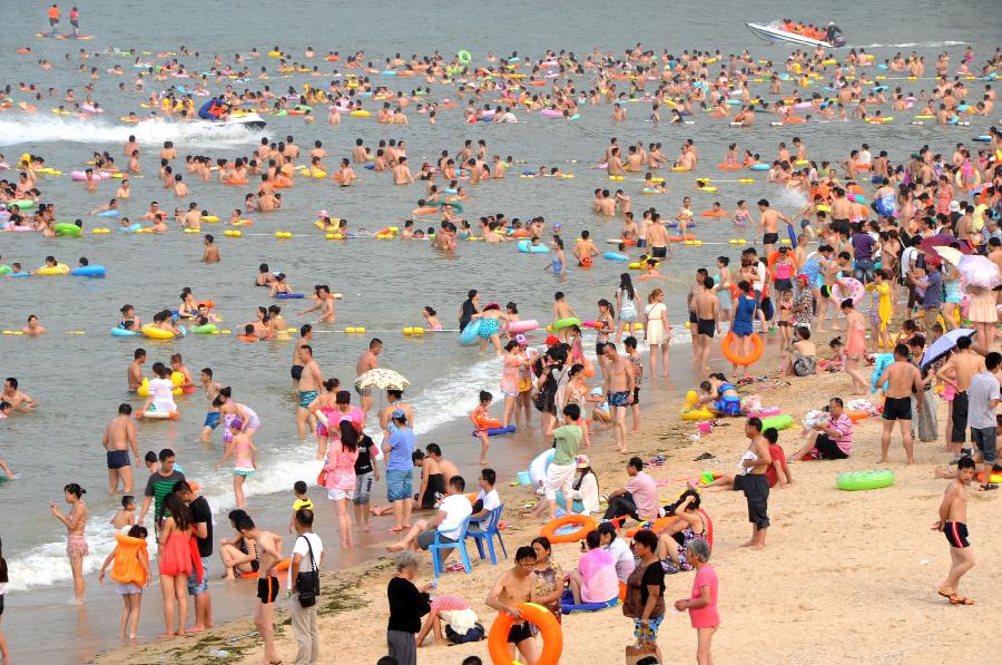 Tourists enjoy coolness at the Dashawan bathing beach in Lianyungang, east China's Jiangsu Province, July 6, 2013. The beach entered its tourism peak season with the rising temperature. (Xinhua/Wang Chun) 