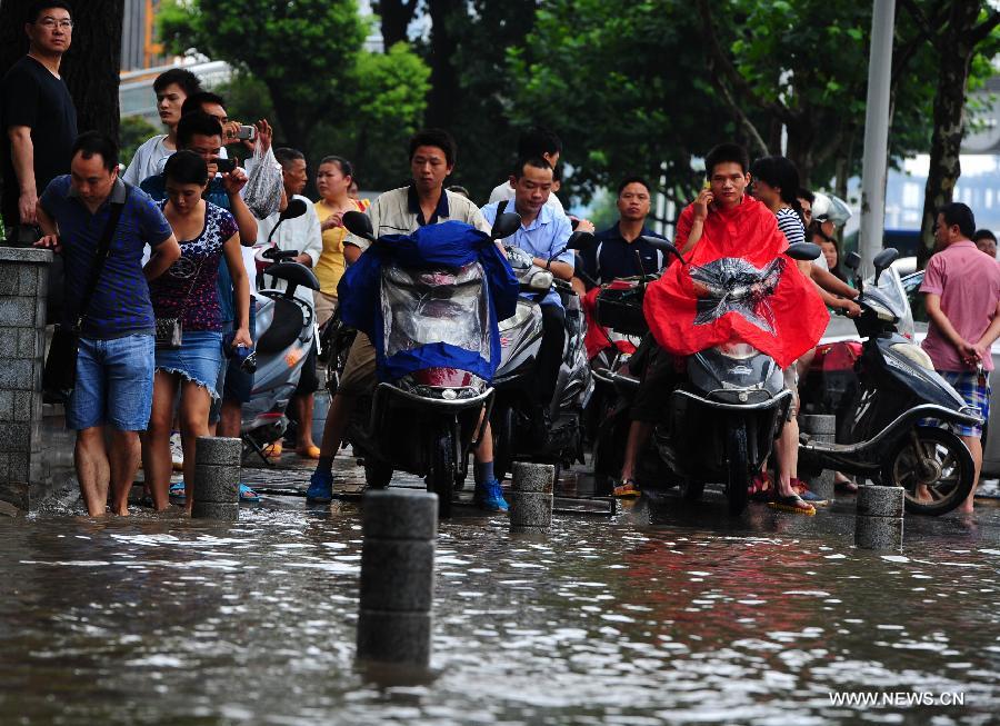 People driving autobikes stop on a flooded road in Wuchang District of Wuhan, capital of central China's Hubei Province, July 7, 2013. Wuhan was hit by the heaviest rainstorm in five years from Saturday to Sunday. The local meteorologic center has issued red alert for rainstorm for many times in sequence. (Xinhua/Xiao Yijiu) 