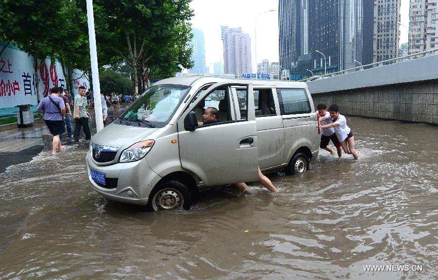 People push a car to the adlittoral area on a flooded road in Wuhan, capital of central China's Hubei Province, July 7, 2013. Wuhan was hit by the heaviest rainstorm in five years from Saturday to Sunday. The local meteorologic center has issued red alert for rainstorm for many times in sequence. (Xinhua/Cheng Min) 