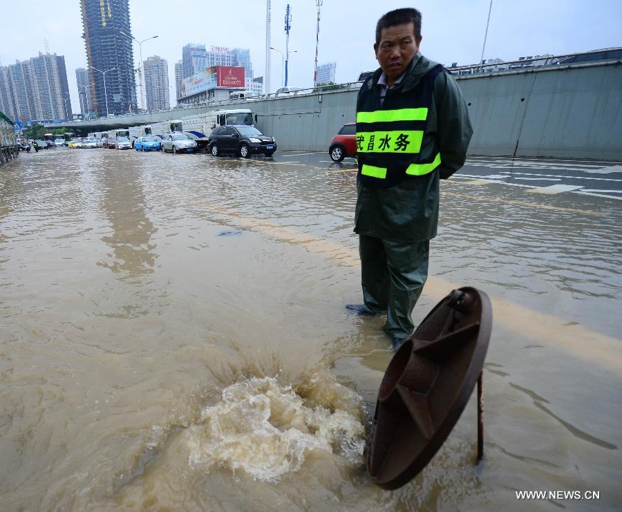 A worker opens a manhole to drain the flood water in Wuhan, capital of central China's Hubei Province, July 7, 2013. Wuhan was hit by the heaviest rainstorm in five years from Saturday to Sunday. The local meteorologic center has issued red alert for rainstorm for many times in sequence. (Xinhua/Cheng Min) 