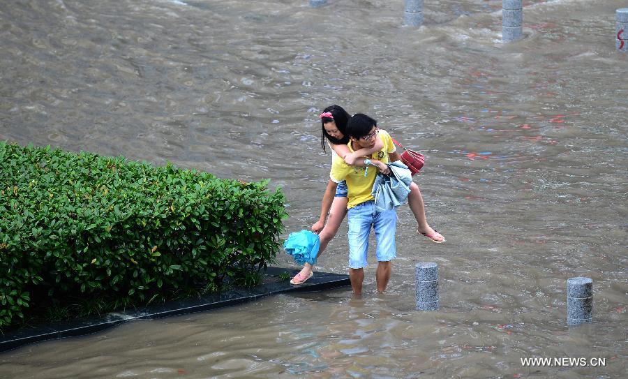 A man carries a woman on a flooded road in Wuhan, capital of central China's Hubei Province, July 7, 2013. Wuhan was hit by the heaviest rainstorm in five years from Saturday to Sunday. The local meteorologic center has issued red alert for rainstorm for many times in sequence. (Xinhua/Cheng Min)