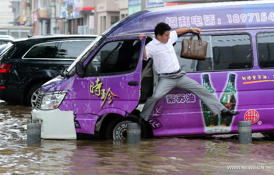 A man gets out of a car on a flooded road in Wuhan, capital of central China's Hubei Province, July 7, 2013. Wuhan was hit by the heaviest rainstorm in five years from Saturday to Sunday. The local meteorologic center has issued red alert for rainstorm for many times in sequence. (Xinhua/Cheng Min) 