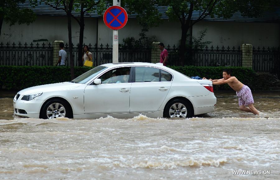 A man pushes a car on a flooded road in Wuhan, capital of central China's Hubei Province, July 7, 2013. Wuhan was hit by the heaviest rainstorm in five years from Saturday to Sunday. The local meteorologic center has issued red alert for rainstorm for many times in sequence. (Xinhua/Cheng Min) 