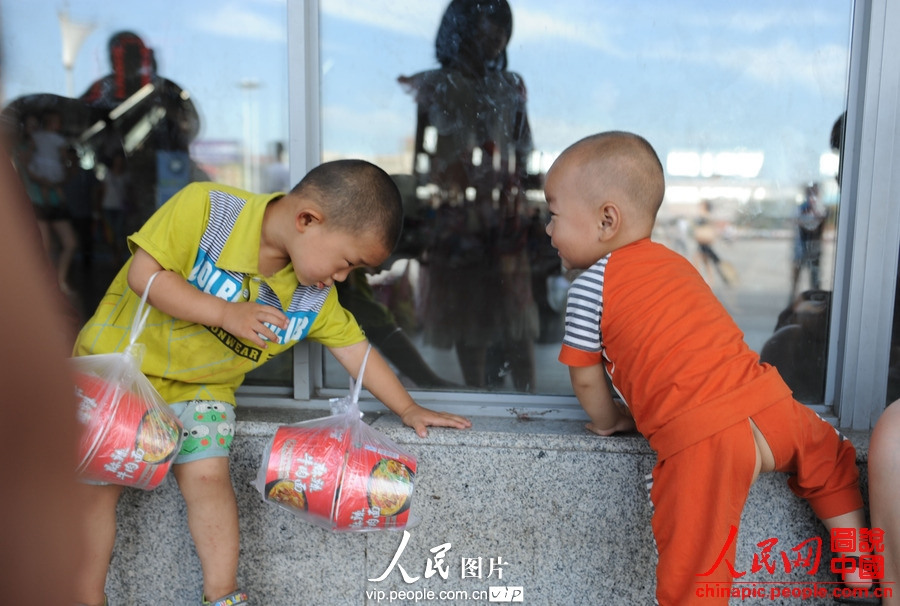 Two children accompanied by adults take the train to spend holidays with their parents working in cities at Fuyang Railway Station, east China's Anhui province, July 2, 2013. (photo/vip.people.com.cn)