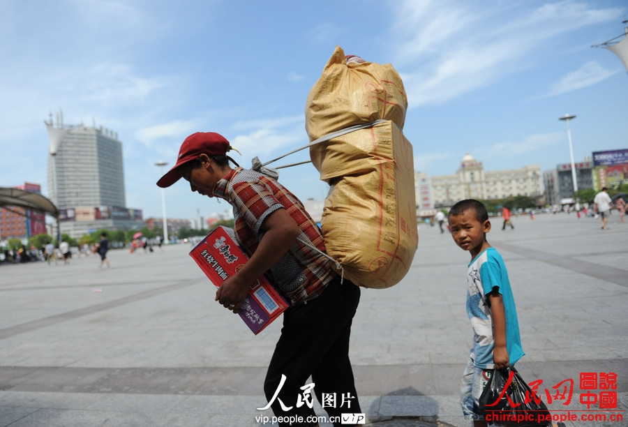 A child accompanied by adult waits for the train at the square of Fuyang Railway Station, east China's Anhui province, July 2, 2013. (photo/vip.people.com.cn)