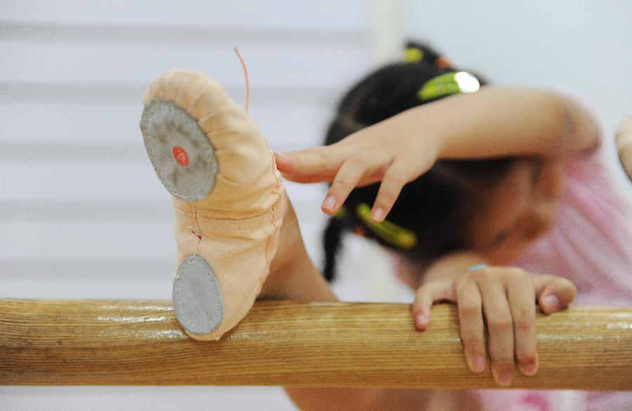 A young girl does physical training at a dance class during the summer vacation in Shanghai, east China, July 7, 2013. (Xinhua/Lai Xinlin)