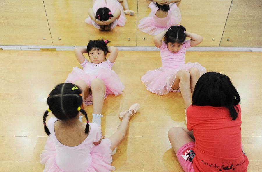 Young girls do physical training at a dance class during the summer vacation in Shanghai, east China, July 7, 2013. (Xinhua/Lai Xinlin)