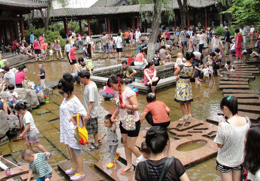 Citizens spend time in waterside leisure zone to beat the heat in the Wulongtan Park in Jinan, capital of east China's Shandong Province, July 8, 2013. The highest temperature in urban Jinan hit 35 degrees Celsius on Monday. (Xinhua/Xu Suhui)