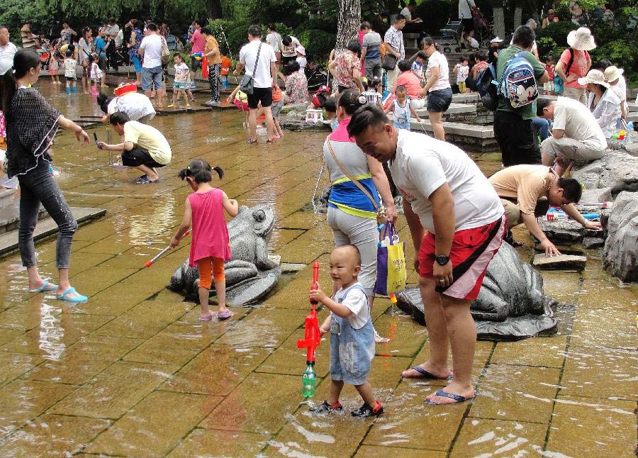 Citizens spend time in waterside leisure zone to beat the heat in the Wulongtan Park in Jinan, capital of east China's Shandong Province, July 8, 2013. The highest temperature in urban Jinan hit 35 degrees Celsius on Monday. (Xinhua/Xu Suhui)