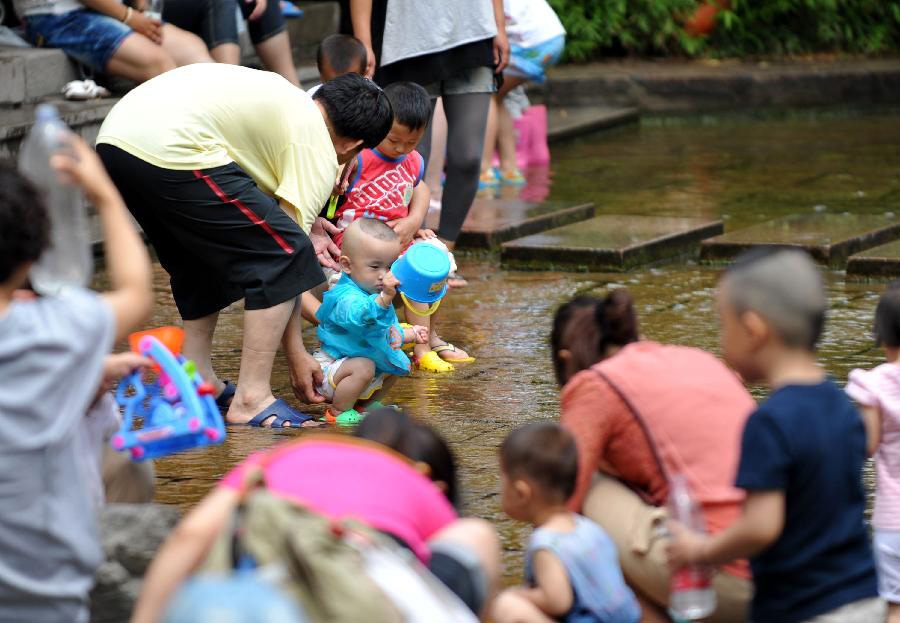 A child enjoy himself in waterside leisure zone to beat the heat in the Wulongtan Park in Jinan, capital of east China's Shandong Province, July 8, 2013. The highest temperature in urban Jinan hit 35 degrees Celsius on Monday. (Xinhua/Xu Suhui)