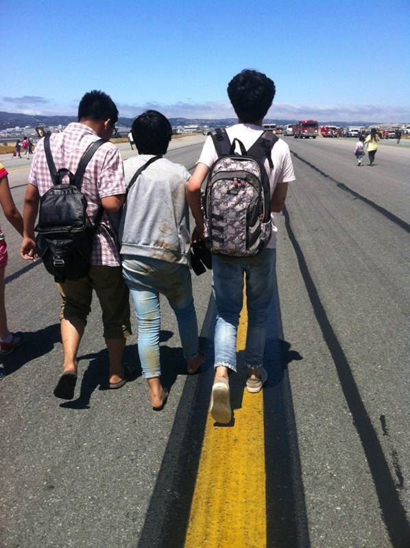 Several survivors help each other to leave the scene of the accident at San Francisco International Airport in San Francisco, the U.S., July 6, 2013. (Photo/Xinhua)