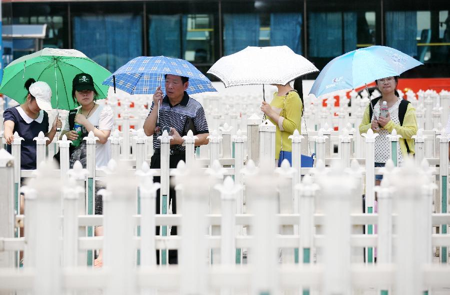 Citizens are waiting at a bus stop in the heat in Nanjing City, capital of east China's Jiangsu Province, July 8, 2013. The rainy season ends on Monday July 8 and high temperature may hit 36 degrees Celsius in a few days in the southern Huaihe River region in east China's Jiangsu Province, according to the local meteorological observatory. (Xinhua/Huangzhe)