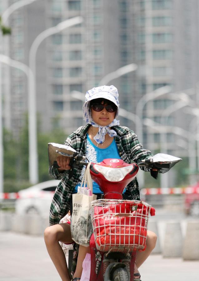 A citizen rides in a street in Nantong City, east China's Jiangsu Province, July 8, 2013. The rainy season ends on Monday July 8 and high temperature may hit 36 degrees Celsius in a few days in the southern Huaihe River region in east China's Jiangsu Province, according to the local meteorological observatory. (Xinhua/Huangzhe)