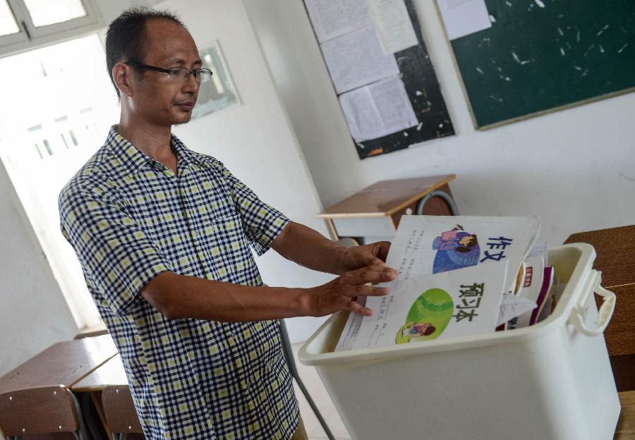 Jiang Jianming, the Chinese teacher of Wang Linjia, puts Wang's books away at Jiangshan Middle School in Jiangshan, east China's Zhejiang Province, July 8, 2013. Two Chinese passengers, Wang Linjia and Ye Mengyuan, were killed in a crash landing of an Asiana Airlines Boeing 777 at the San Francisco airport on Saturday morning. The two girls are both students of Jiangshan Middle School. Their family members headed for the United States on Monday.(Xinhua/Han Chuanhao)