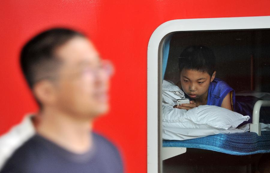 A child sends text messages on a train at the Yinchuan Railway Station in Yinchuan, capital of northwest China's Ningxia Hui Autonomous Region, July 8, 2013. China's summer railway travel rush officially started on July 1 and will last until Aug. 31. (Xinhua/Peng Zhaozhi)