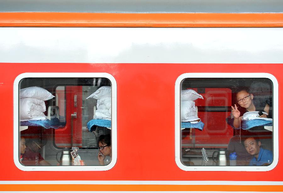 Passengers wait in a train for departure at the Yinchuan Railway Station in Yinchuan, capital of northwest China's Ningxia Hui Autonomous Region, July 8, 2013. China's summer railway travel rush officially started on July 1 and will last until Aug. 31. (Xinhua/Peng Zhaozhi)