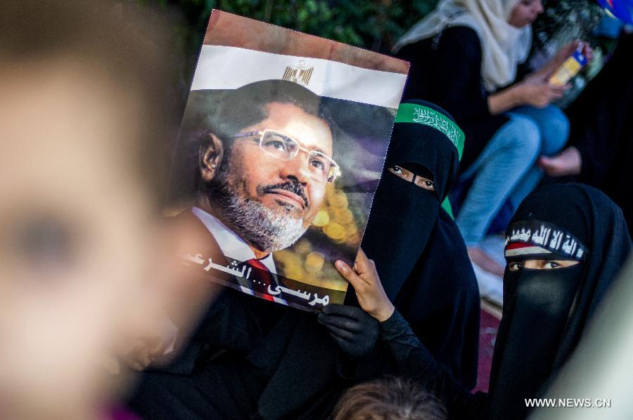 A supporter of ousted Egyptian president Mohamed Morsi holds a poster of Morsi as she rests in a tent outside Raba al-Adwyia Mosque, in Nasr City, Cairo, capital of Egypt, July 8, 2013. (Xinhua/Li Muzi) 