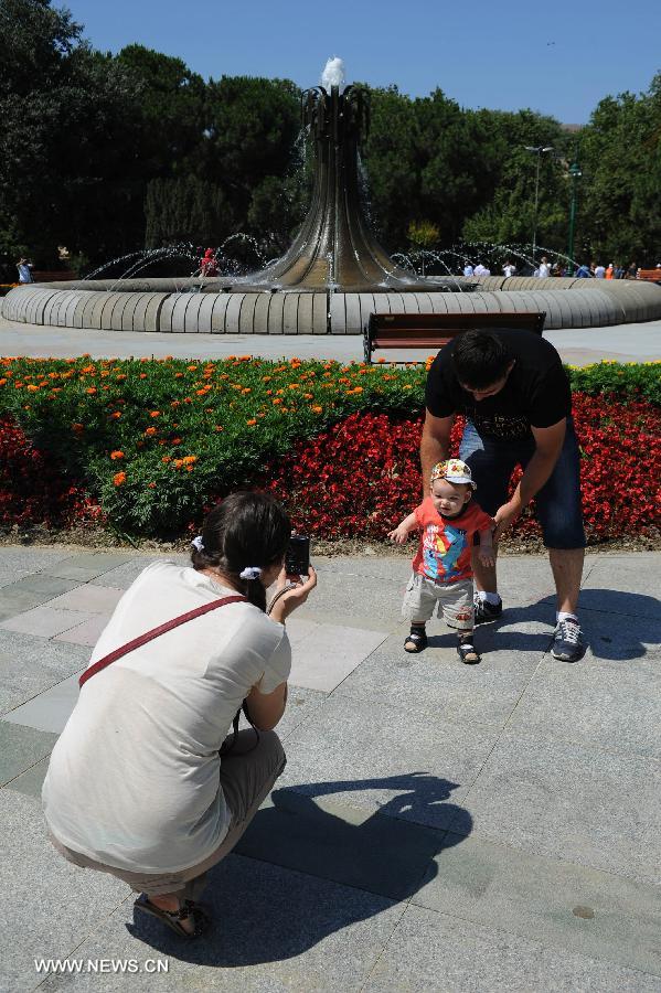 A parent takes pictures for their baby in the Gezi park in Istanbul on July 8, 2013. Turkey's Gezi Park was opened to the public Monday after a week-long closure, Istanbul Governor Huseyin Avni Mutlu announced. (Xinhua/Lu Zhe)