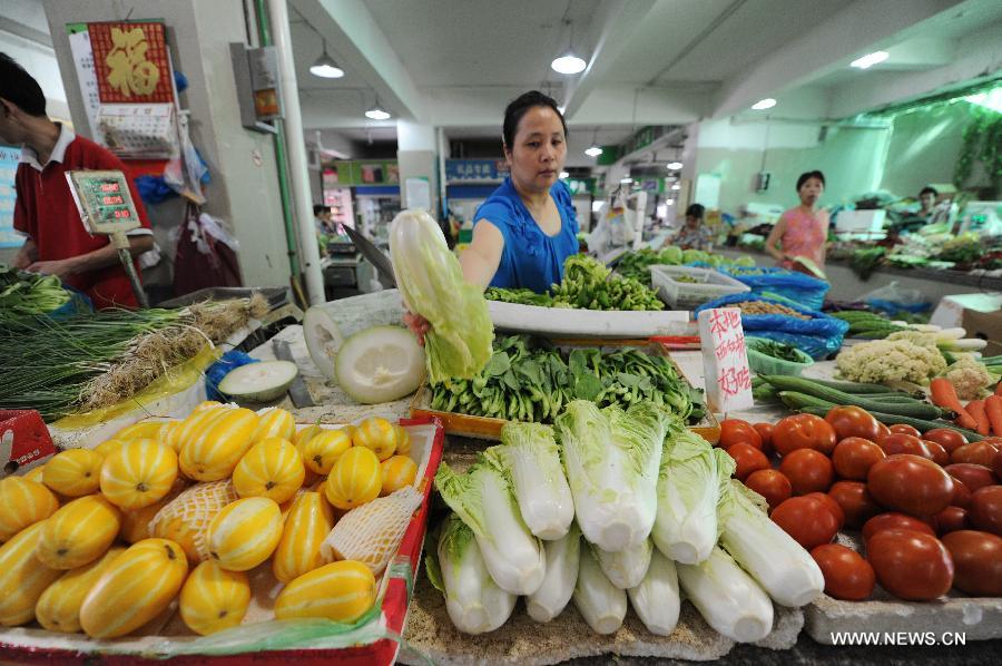 A seller arranges vegetables at a market in Hangzhou, capital of east China's Zhejiang Province, July 9, 2013. China's consumer price index (CPI), a main gauge of inflation, grew 2.7 percent year on year in June, up from 2.1 percent in May, the National Bureau of Statistics said on Tuesday. (Xinhua/Ju Huanzong) 