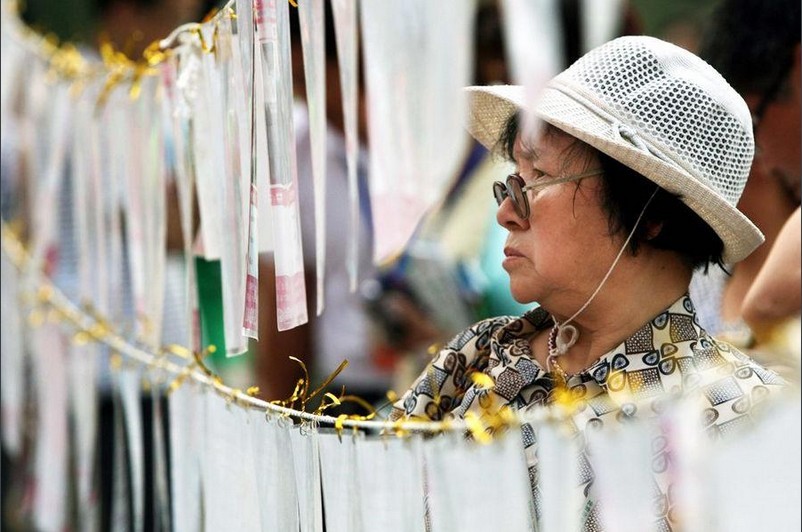 A mother reads information of unmarried youngsters. Parents attend the blind date event in parks, keeping an eye out for suitable future in-laws, not for themselves, but for their children. 