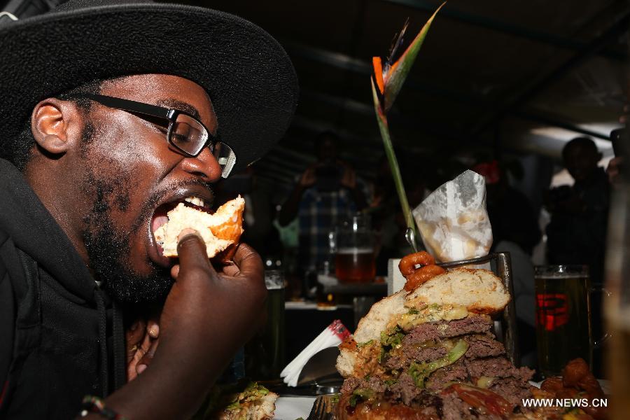 A contestant takes part in a burger challenge at Brew Bistro in Nairobi, capital of Kenya, July 9, 2013. Four contestants had one hour to finish a 5kg burger with beef, two huge burger buns and 40 toppings. Sauti Sol team won the burger challenge. (Xinhua/Meng Chenguang)