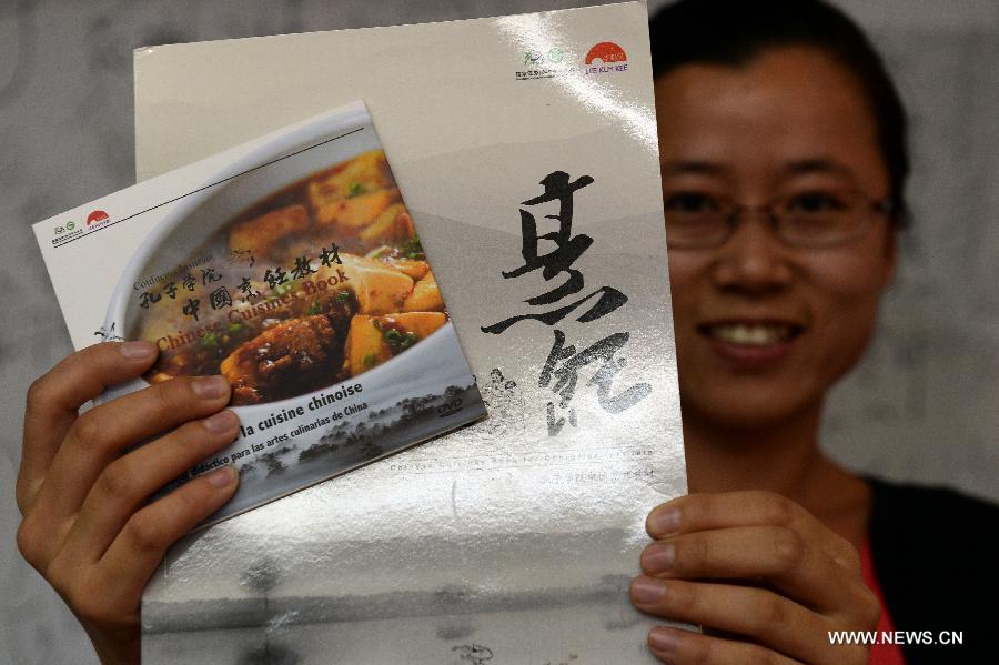 A volunteer heading for America presents the Chinese cuisine book of Confucius Institute in Beijing, capital of China, July 9, 2013. Chinese cuisine book written by Confucius Institute and Lee Kun Kee Food Co., Ltd. was officially released on Tuesday. (Xinhua/Jin Liangkuai)