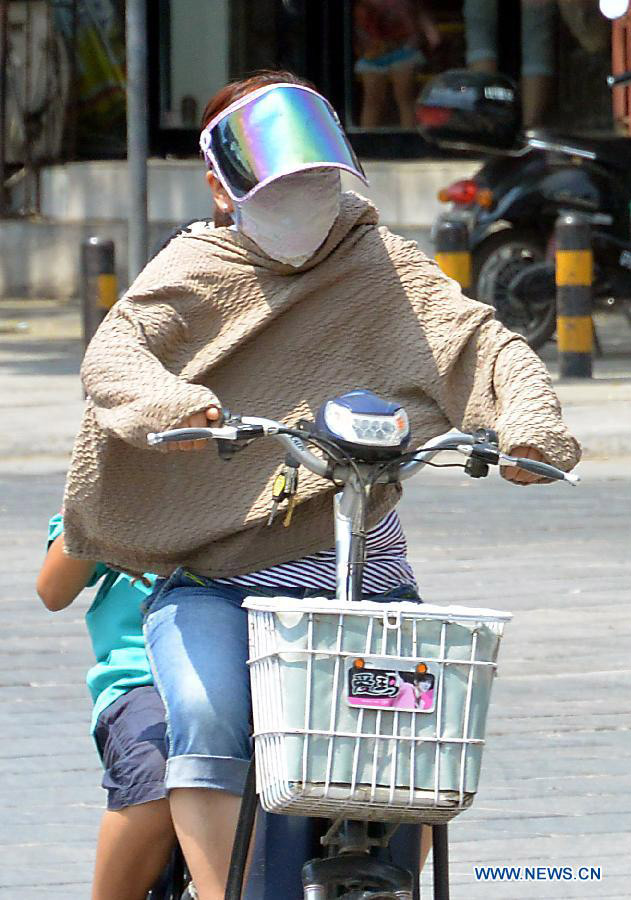 A woman rides on a road as heat wave hits Shangqiu City, central China's Henan Province, July 10, 2013. The highest temperature reached 37 degrees Celsius in the city on Wednesday. (Xinhua/Wang Song)