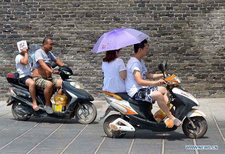 Citizens ride on a road as heat wave hits Shangqiu City, central China's Henan Province, July 10, 2013. The highest temperature reached 37 degrees Celsius in the city on Wednesday. (Xinhua/Wang Song)